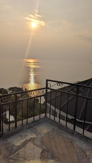 A sunrise over a calm sea with a railing in the foreground. 5