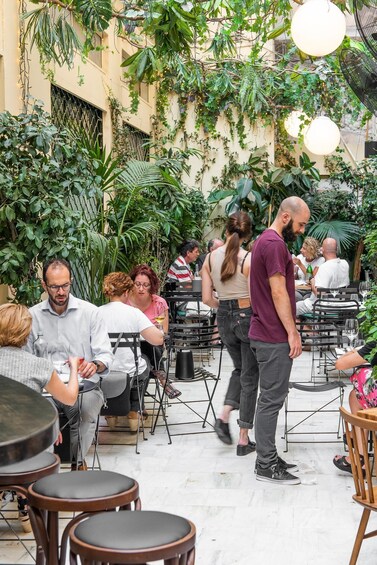 An outdoor cafe with tables and chairs, surrounded by lush greenery and hanging plants. 3