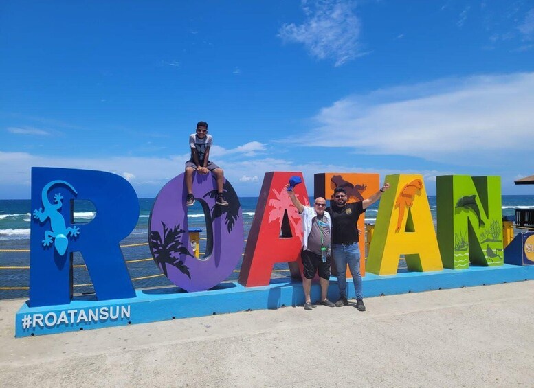 A beach with large colorful letters spelling 'ROATANSUN' and a seagull sculpture. 3