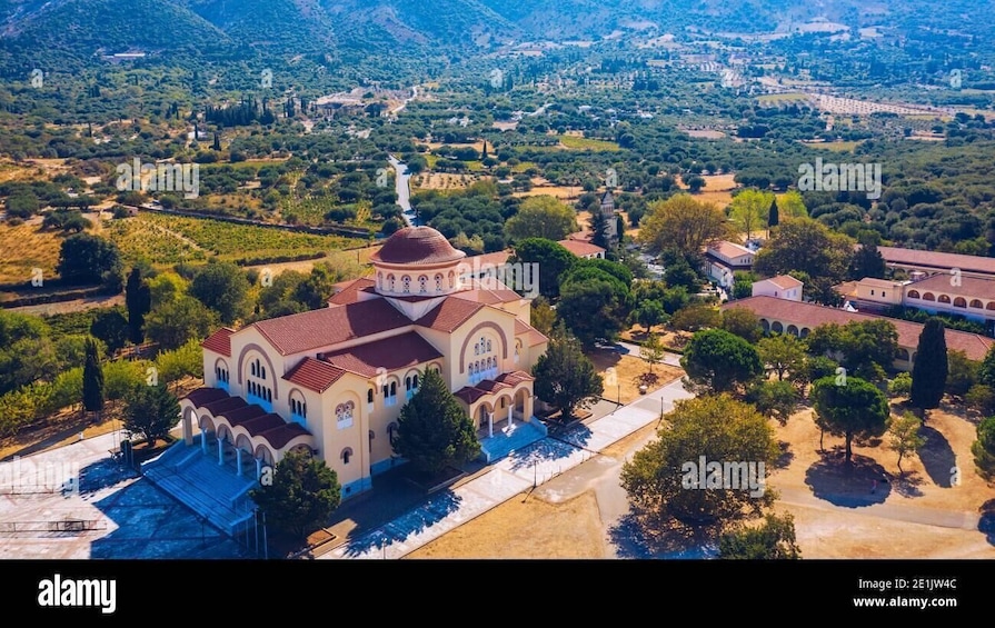 An aerial view of a church with a dome, surrounded by trees and a valley. 3