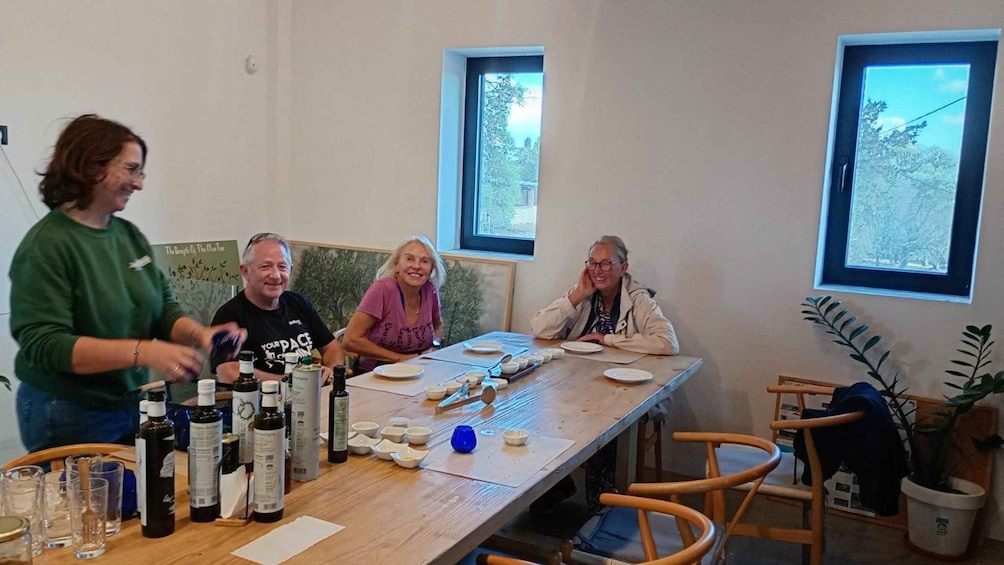 A group of people at a table with various bottles and glasses, possibly for a tasting event. 2
