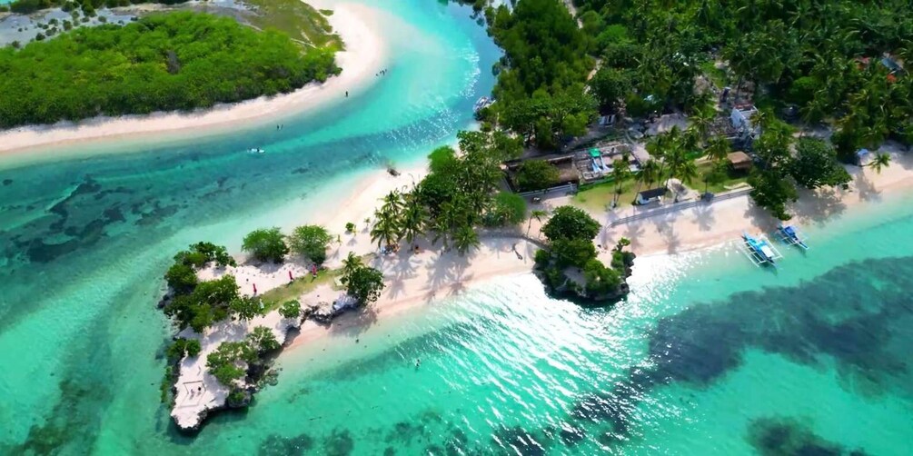 An aerial view of a tropical island with clear turquoise waters, sandy beaches, and lush greenery. 5