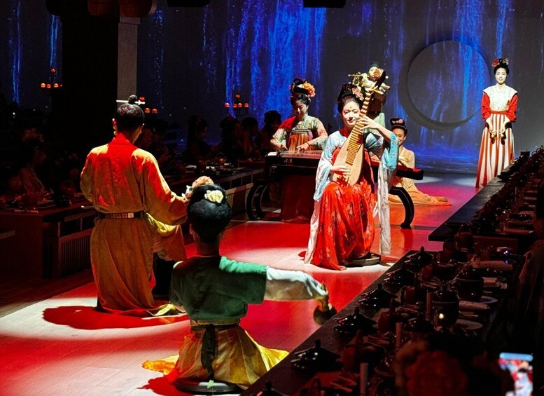 A traditional performance with actors in historical costumes on a stage with a backdrop of blue lighting. 2