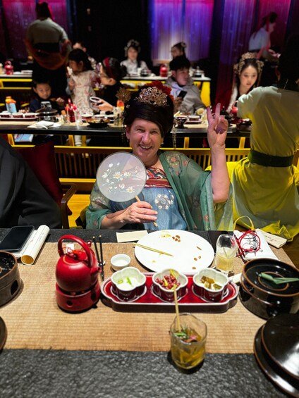 A person at a table with a traditional fan, chopsticks, and various dishes. 5