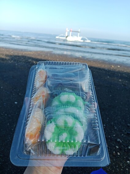 A person holding a plastic container with food items on a beach. 2