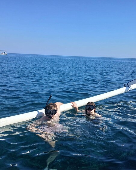 Two people snorkeling in the ocean with a boat in the background. 4
