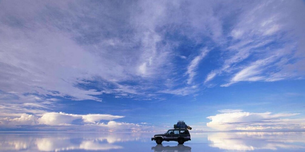 A vehicle on a reflective surface with a clear sky above. 3