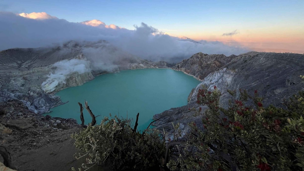 A turquoise lake surrounded by rugged terrain and volcanic activity. 1