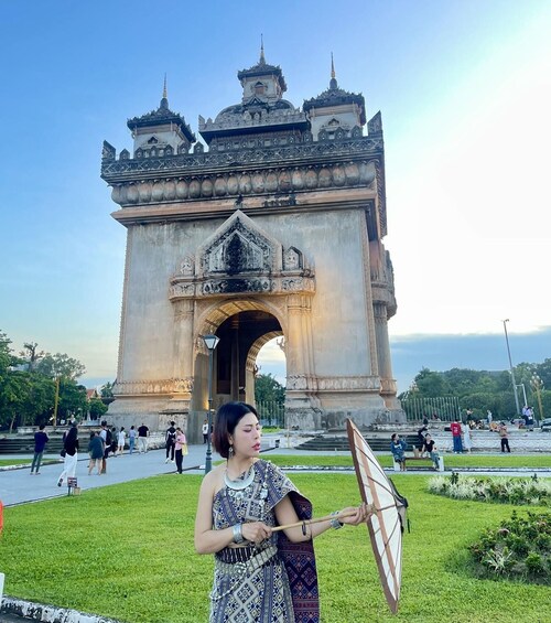 A person holding a kite in front of a large, ornate gate. 2