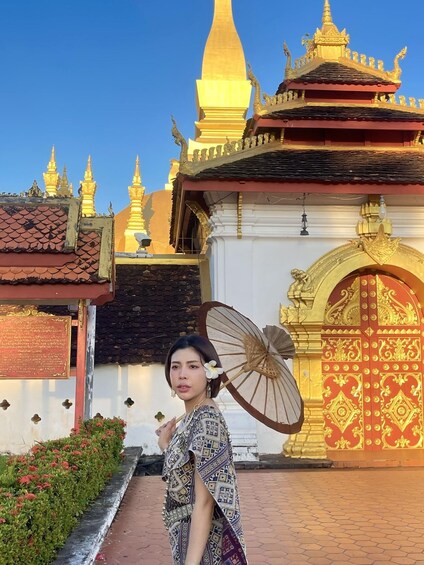 A person standing in front of a temple with golden spires and a red and white gate. 1