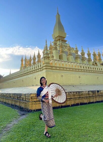 A person in traditional attire holding an umbrella in front of a temple with multiple spires. 5