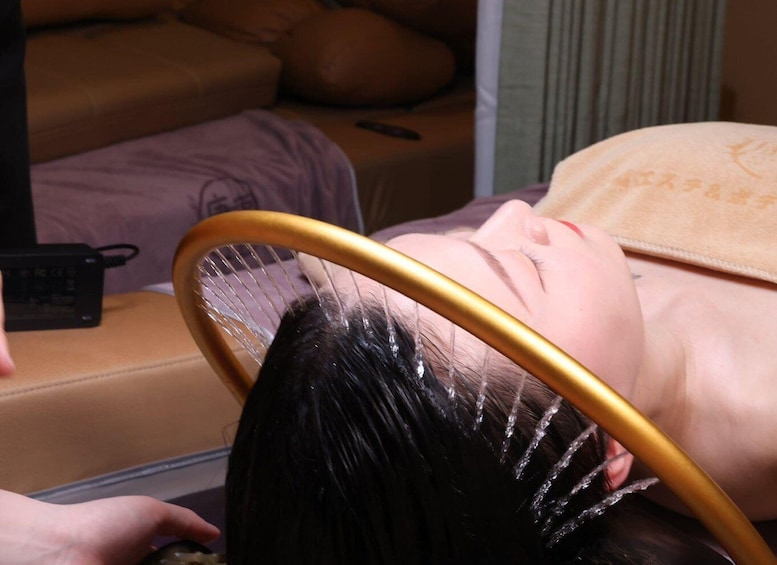 A person lying down with a headrest, a remote control, and a power adapter on a couch. 1