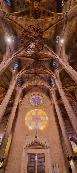 A cathedral interior with a large circular stained glass window, arched ceilings, and a central chandelier. 4