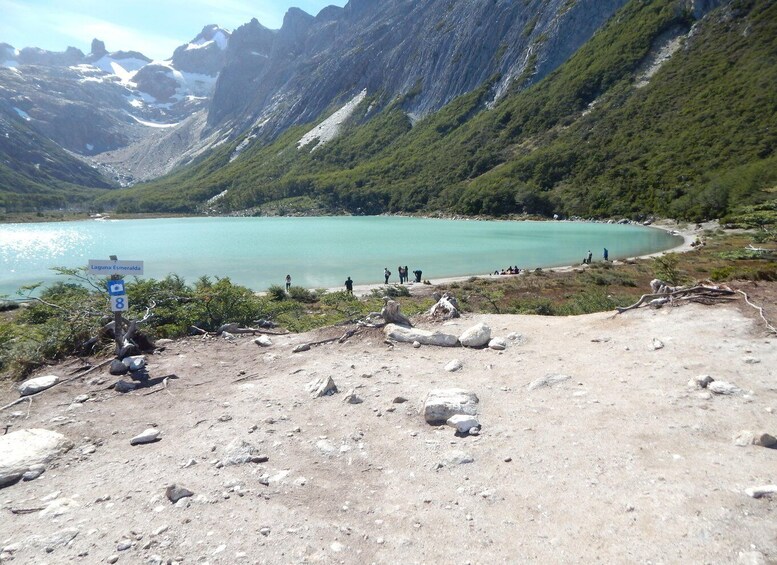 A mountainous landscape with a turquoise lake, a rocky beach, and a sign indicating 'Laguna Esmeralda.' 3