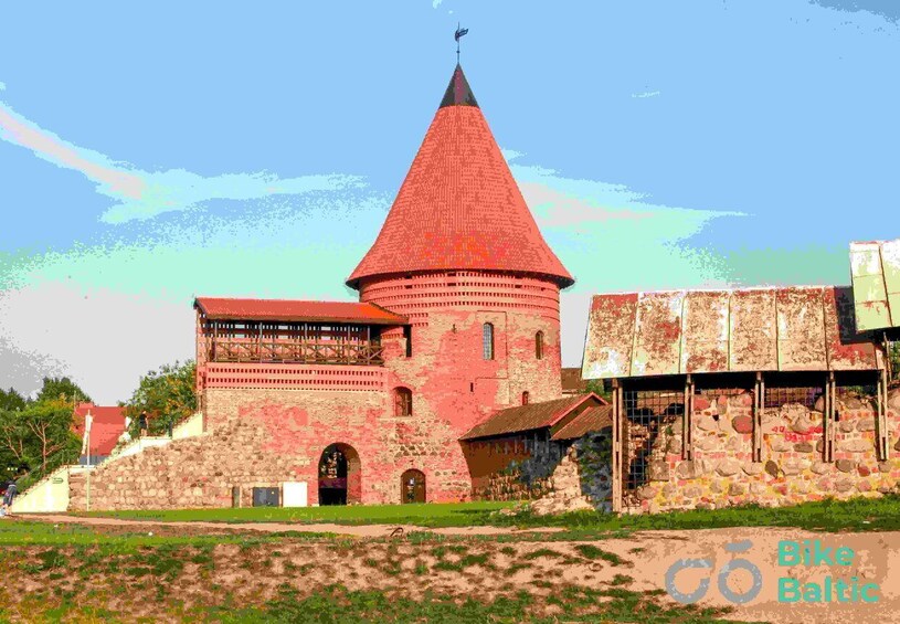 A historic brick building with a conical tower and a wooden structure in front. 3