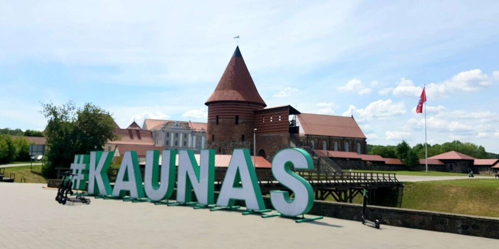 A historic building with a prominent tower and a large sign reading 'KAUNAS.' 1
