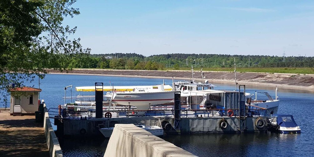 A dock with boats, a small building, and a forested shoreline. 2