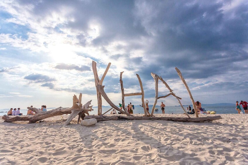 A sandy beach with driftwood structures and people relaxing. 5