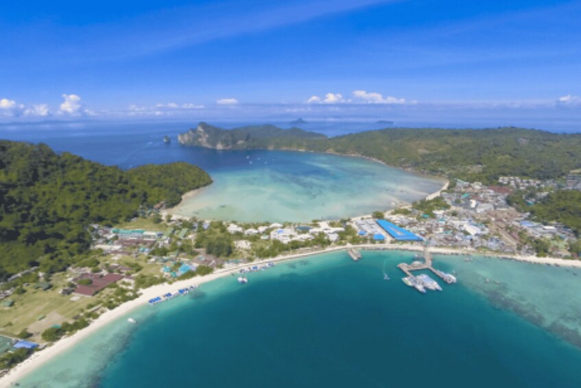 An aerial view of a coastal town with clear turquoise waters, a marina, and lush green hills. 3