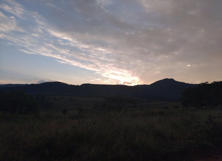 A sunset over a hilly landscape with sparse vegetation. 5