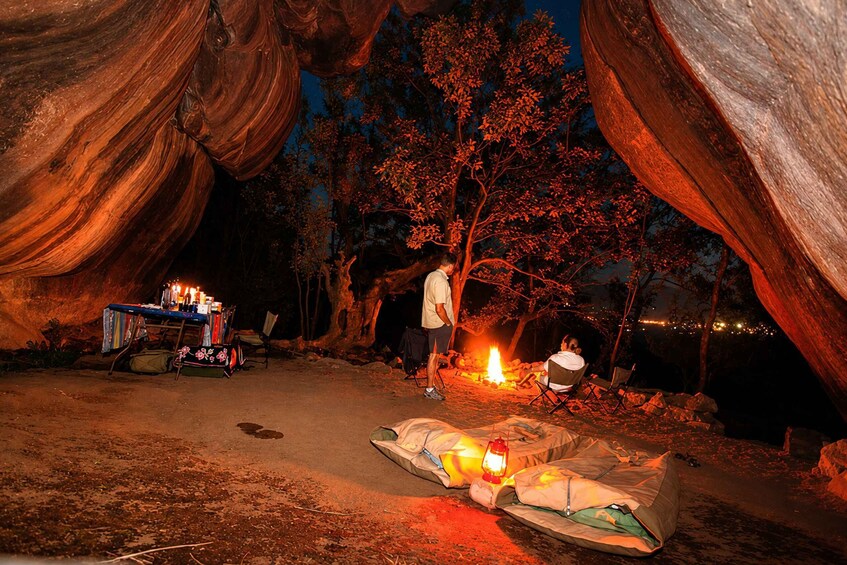 A campsite at night with a fire, tents, and a table with candles. 1
