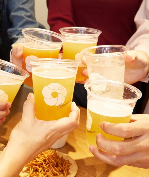 People holding plastic cups with a yellow beverage, possibly beer, and a plate of fried snacks. 5