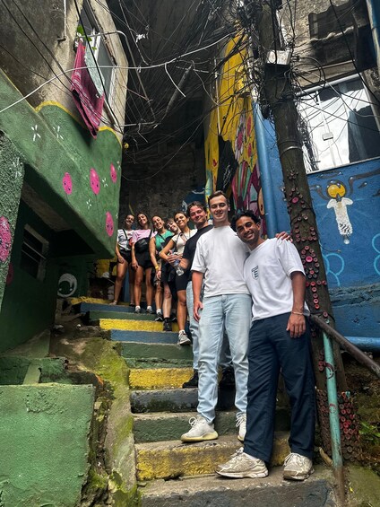 A group of people standing on colorful, graffiti-covered stairs in an urban setting. 1
