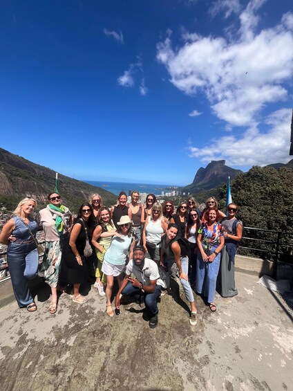 A group of people posing on a concrete platform with a scenic view of a coastal landscape and mountains in the background. 2