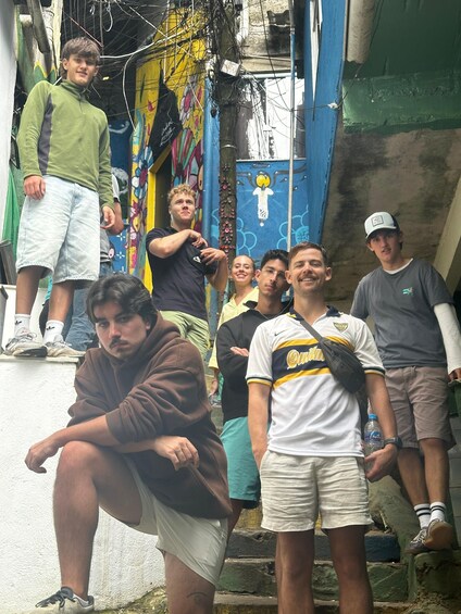 A group of people standing in an alley with colorful murals and a blue wall. 3