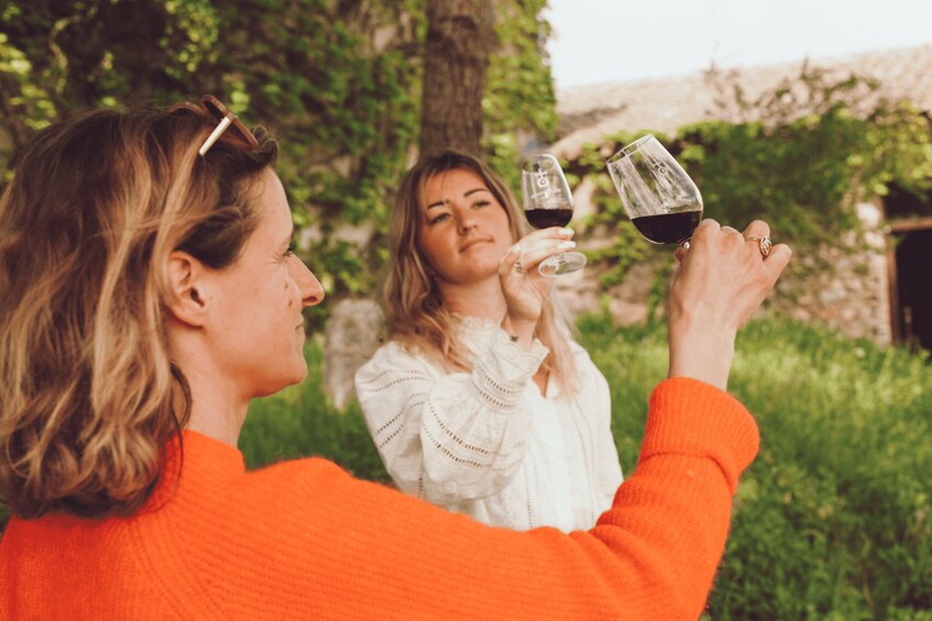 Two people toasting with wine glasses in a garden with trees and greenery. 2