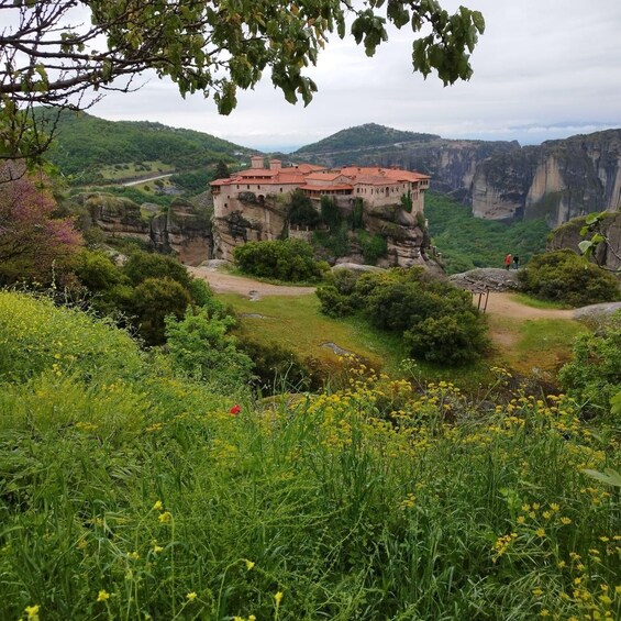 A historic building perched atop a cliff, surrounded by lush greenery and a valley. 1
