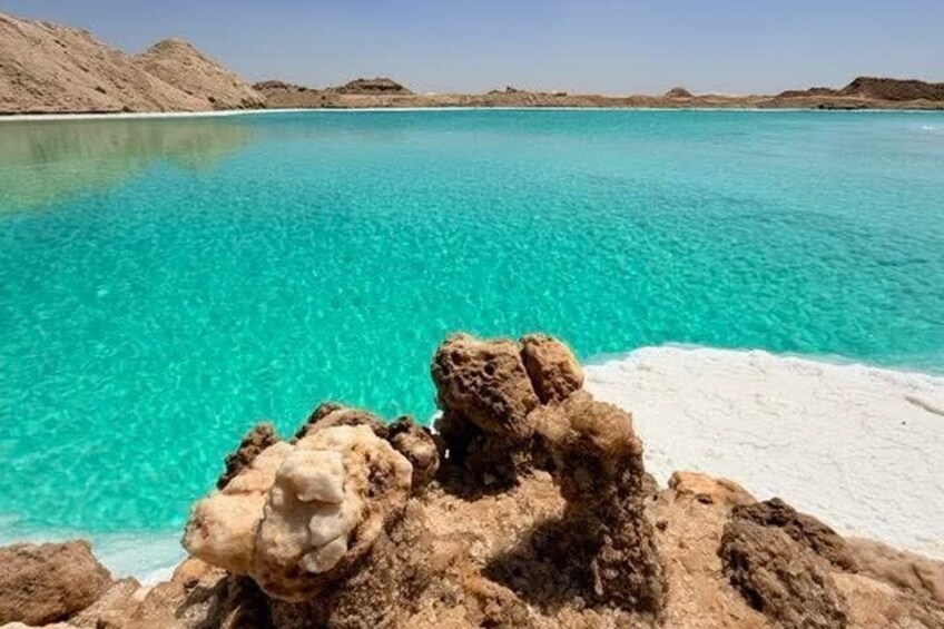 A clear turquoise sea, rocky formations, and a white sandy beach. 1