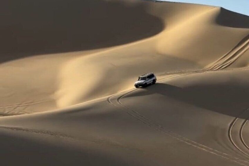 A vehicle navigating a sand dune landscape. 5