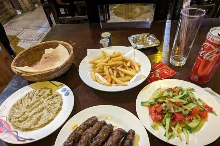 A table with various dishes including fries, a salad, and a plate of meat. 3