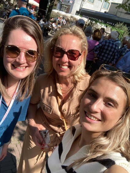 Three people in an outdoor setting with a crowd in the background. 5