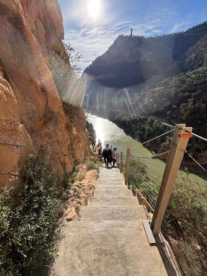 A concrete staircase leading down to a river, surrounded by rocky terrain and greenery. 5