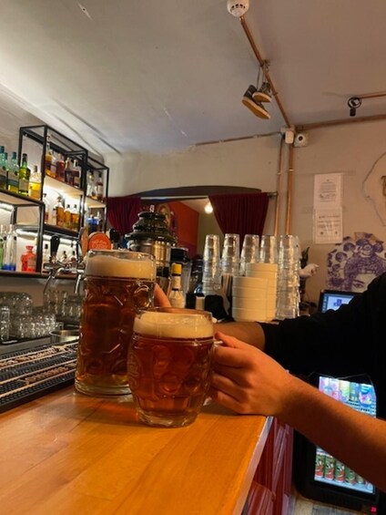 A bar with large beer mugs and a person holding one. 4
