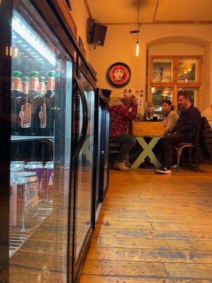 A bar with a refrigerator stocked with beverages, wooden flooring, and a wall with a circular artwork. 5