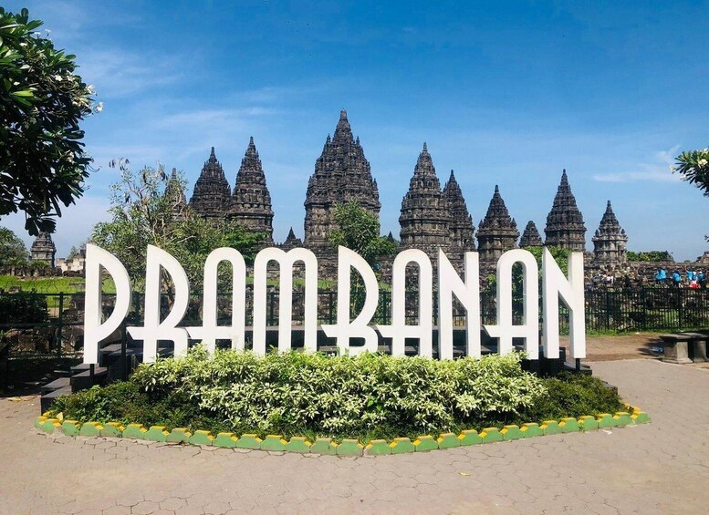 Skilt med 'PRAMBANAN' foran gamle stenhuse. 1