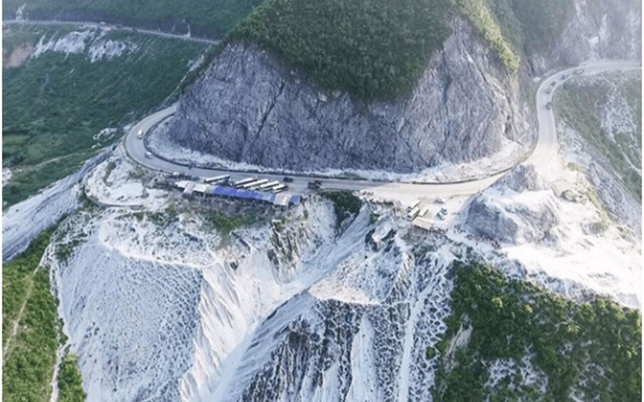 A road winding through a mountainous area with a steep cliff and a small bridge. 1