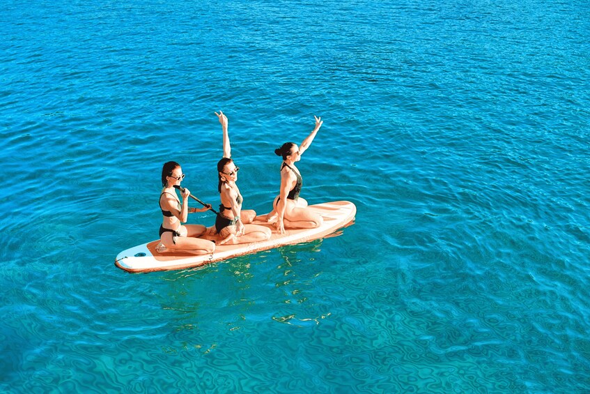 Two people on a surfboard in clear blue water. 4