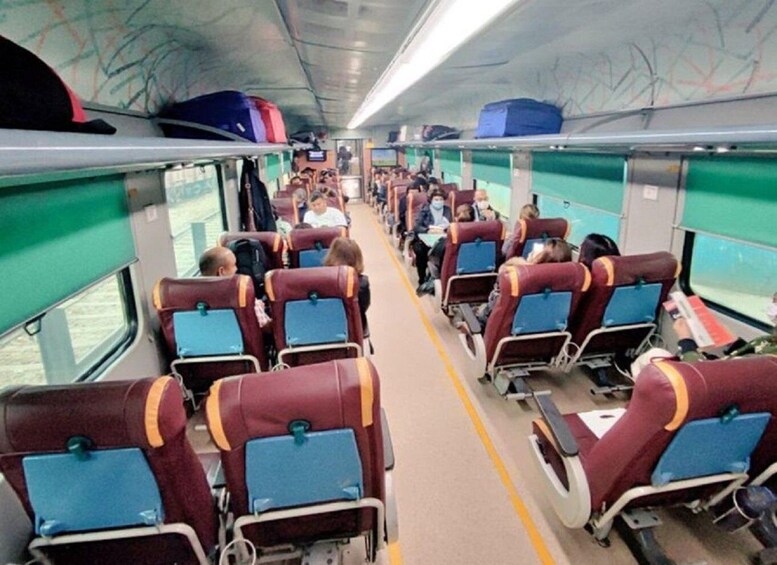 A train carriage with rows of seats, some occupied by passengers. 4