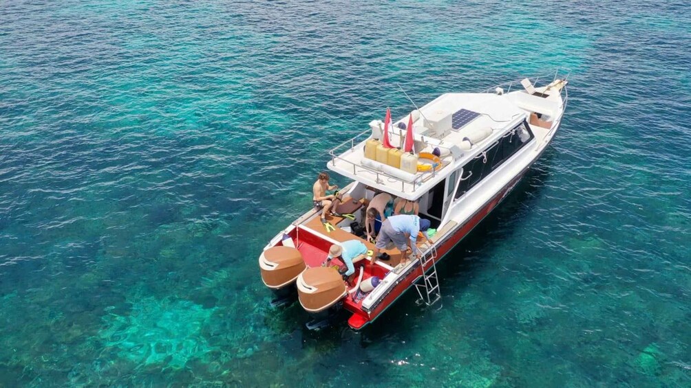 A boat with passengers and a lifebuoy on clear turquoise water. 4