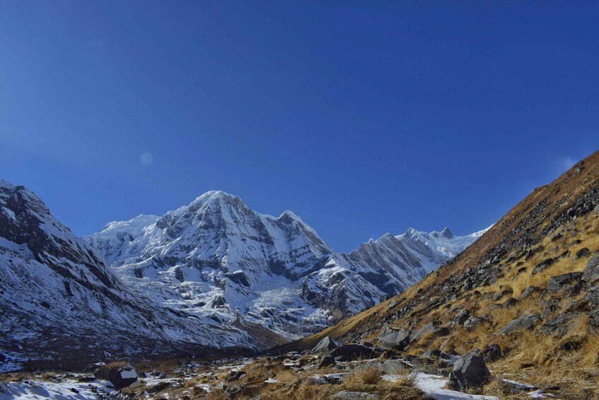 A snow-covered mountain range with rocky terrain and a clear blue sky. 4