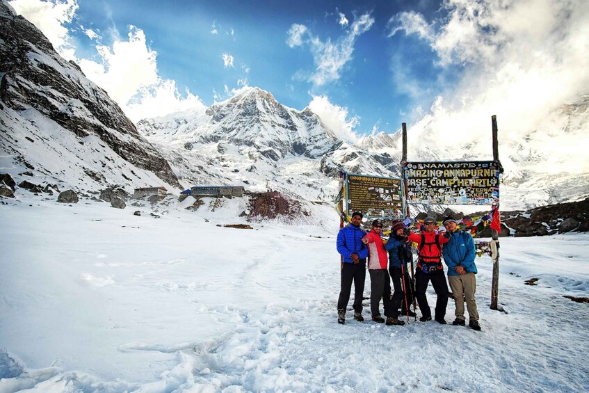 A group of people standing in a snowy landscape with a signboard in the background. 5