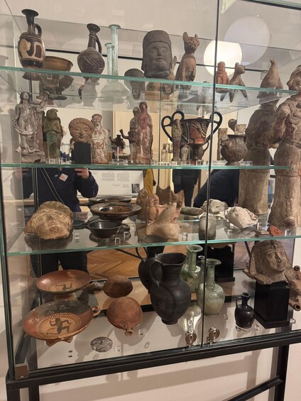 A museum display of ancient artifacts including pottery, sculptures, and figurines. 5