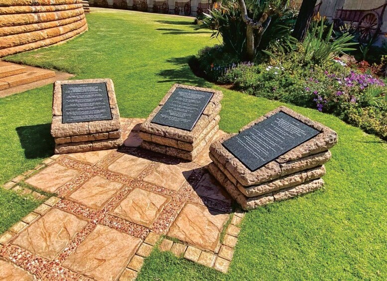 A garden with stone planters and plaques, surrounded by well-maintained grass and flowering plants. 4