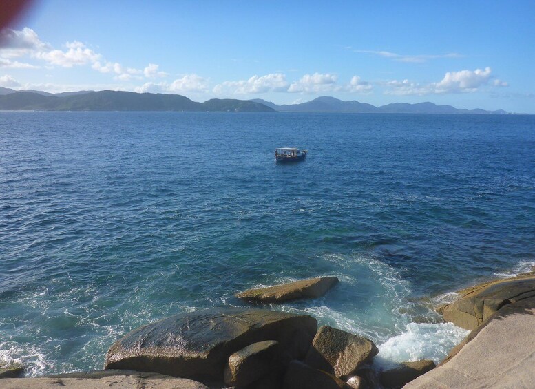 A boat on a calm sea with rocky shores and distant mountains. 3