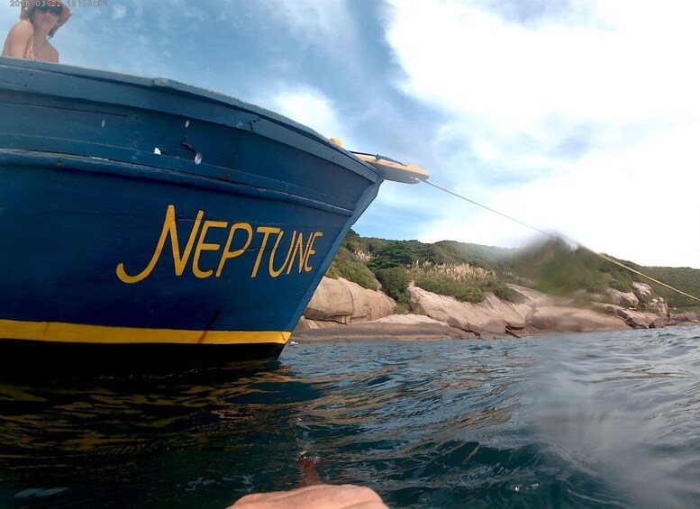 A boat named 'NEPTUNE' with a rocky shoreline in the background. 2