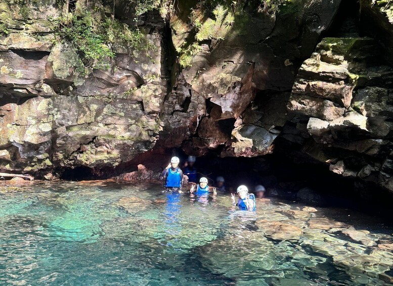 A group of people kayaking in a clear, rocky waterway surrounded by cliffs. 3